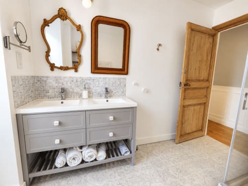 Salle de bain élégante aux Chambres D'Hespéris à Pleyben avec double vasque, miroirs en bois et rangements pour serviettes
