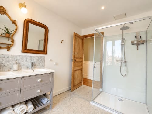 Salle de bain moderne aux Chambres D'Hespéris à Pleyben avec douche à l'italienne, meuble vasque en bois et miroir doré