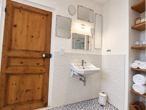 Salle de bains moderne aux Chambres D'Hespéris à Pleyben : carrelage blanc, étagères bois, miroirs et sol à motifs