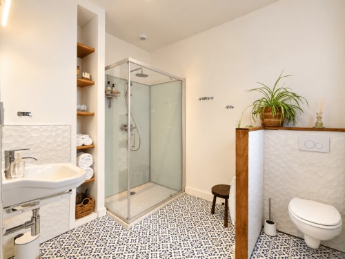 Salle de bain moderne de la chambre Aurore aux Chambres D'Hespéris B&B à Pleyben, avec douche vitrée, lavabo, toilettes et carrelage décoratif