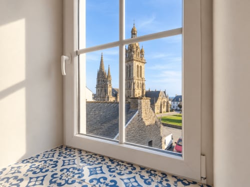 Vue depuis la chambre Aurore aux Chambres D'Hespéris sur les tours de l'église de Pleyben et les bâtiments en pierre historiques de Bretagne