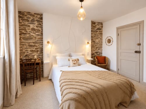 Chambre Aurore aux Chambres D'Hespéris à Pleyben : murs de pierre, literie blanche et éclairage ambiant