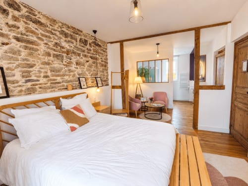 Chambre Solstice aux Chambres D'Hespéris à Pleyben : lit en bois, murs en pierre apparente et vue sur le jardin