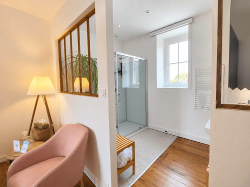 Chambre Solstice aux Chambres D'Hespéris avec salle d'eau privée, fauteuil rose et vue sur le jardin à Pleyben