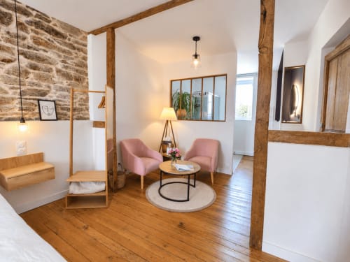 Salon Solstice aux Chambres D'Hespéris, Pleyben, avec fauteuils roses, poutres en bois et vue sur le jardin