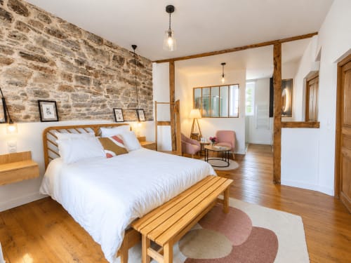 Chambre Solstice aux Chambres D'Hespéris à Pleyben avec lit en bois, mur en pierre et vue sur le jardin