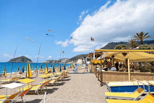 Ombrelloni e lettini gialli sulla spiaggia sabbiosa dell'Hotel Villa Bina Sea a Serrara Fontana, Italia