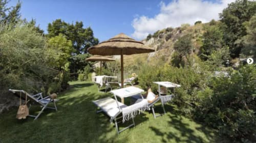 Terrazza giardino del Villa Bina Sea Hotel con lettini, ombrelloni e paesaggio mediterraneo a Serrara Fontana