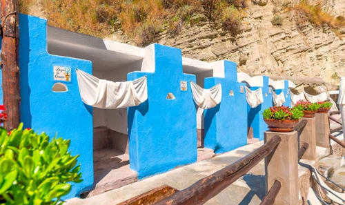 Cabanas blu fronte mare con tende bianche a Villa Bina Sea Hotel a Serrara Fontana, Italia