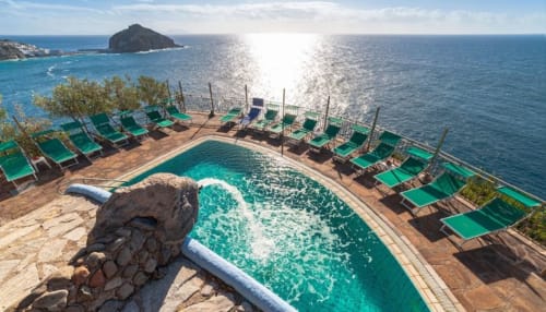 Piscina a sfioro del Villa Bina Sea Hotel a picco sul mare con acqua turchese, lettini verdi e vista sul Tirreno a Serrara Fontana