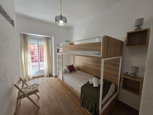 Luminosa habitación con literas en apartamento Brisalena Jerez Centro, suelo de madera, puerta balconera, TV y escritorio.