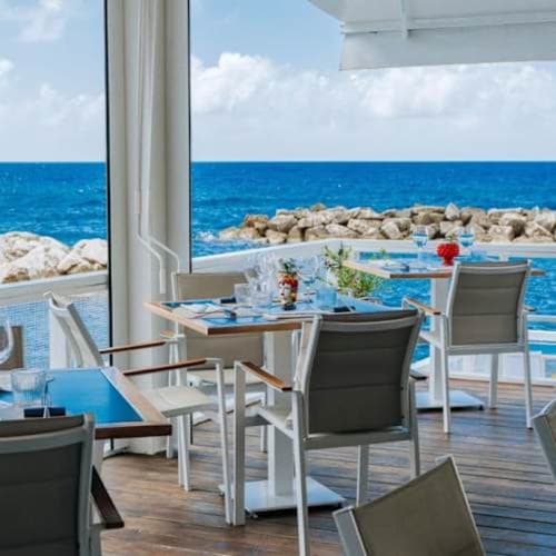 Terrazza ristorazione Villa Bina Sea Hotel con vista mare, sedie bianche e costa rocciosa a Serrara Fontana, Italia