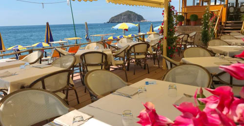 Terrazza ristorazione fronte mare Villa Bina Sea Hotel con vista sul mare, fiori rosa e isole sullo sfondo a Serrara Fontana, Italia