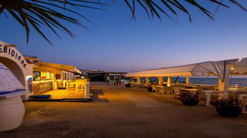 La terrazza fronte mare del Villa Bina Sea Hotel al crepuscolo con i padiglioni illuminati che si affacciano sul mare a Serrara