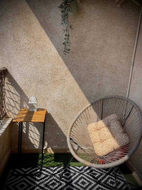 Soleado balcón de Haus Holiday Homes con silla de mimbre, mesa de madera y alfombra estampada en San Pedro del Pinatar