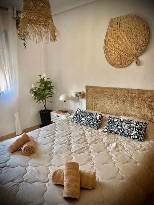 Dormitorio luminoso en Haus Holiday Homes, San Pedro del Pinatar con cabecero tejido, ropa de cama crema, almohadas negras y ambiente costero