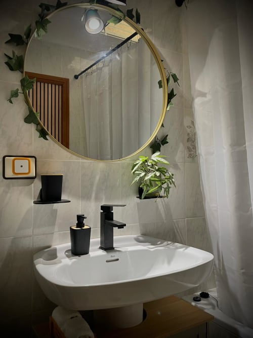 Baño moderno con tocador, espejo con marco dorado, grifería negra y plantas en Haus Holiday Homes, San Pedro del Pinatar