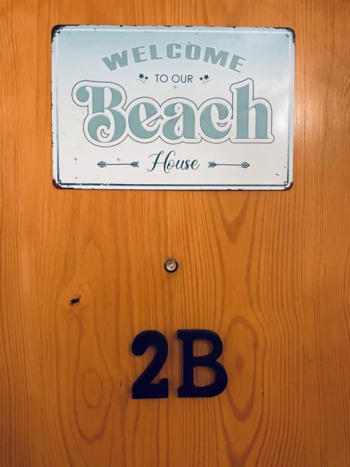Cartel de bienvenida a Casa de Playa con número 2B en puerta de madera en Haus Holiday Homes