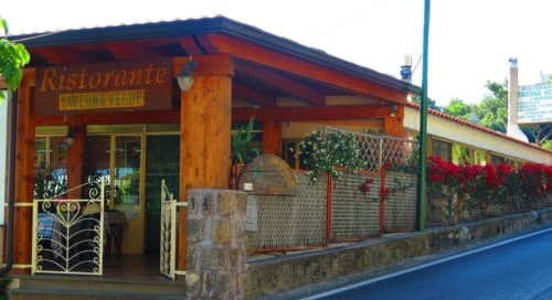 Esterno del ristorante Taverna Verde a Serrara Fontana con architettura in legno e fiori rossi