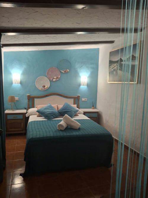 Modern bedroom at Refugio la Presa with turquoise accent wall, wooden bed, blue pillows, wall-mounted decorative plates, and