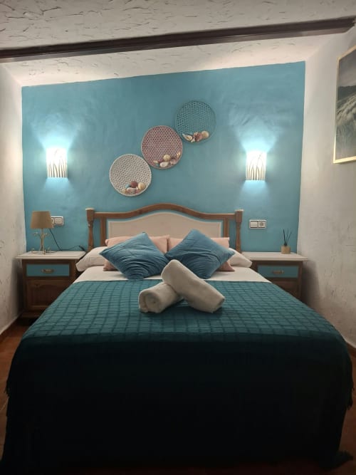 Cozy bedroom at Refugio la Presa with turquoise accent wall, wooden bed frame, decorative plates, and wall sconces