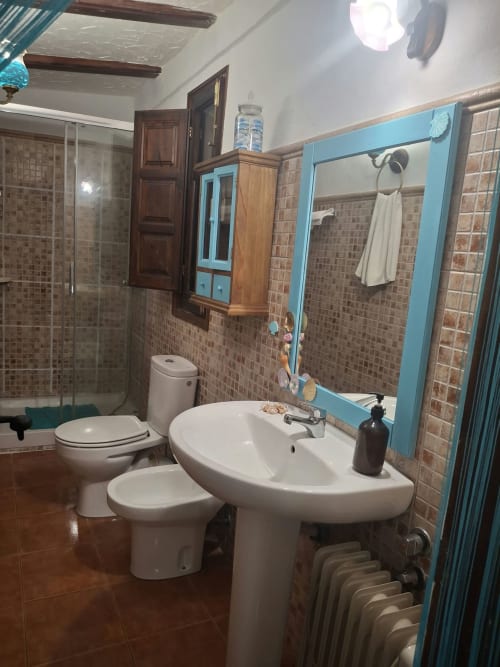 Modern bathroom with pedestal sink, toilet, and large blue-framed mirror at Refugio la Presa in Chulilla