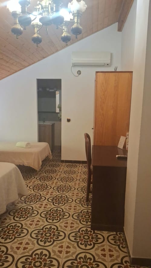 Spacious room at Refugio la Presa in Chulilla with patterned tile floor, bed, wooden furniture, AC unit, and brass ceiling