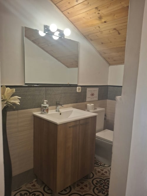 Modern bathroom at Refugio la Presa with wooden vanity, white sink, illuminated mirror, and patterned tile flooring in