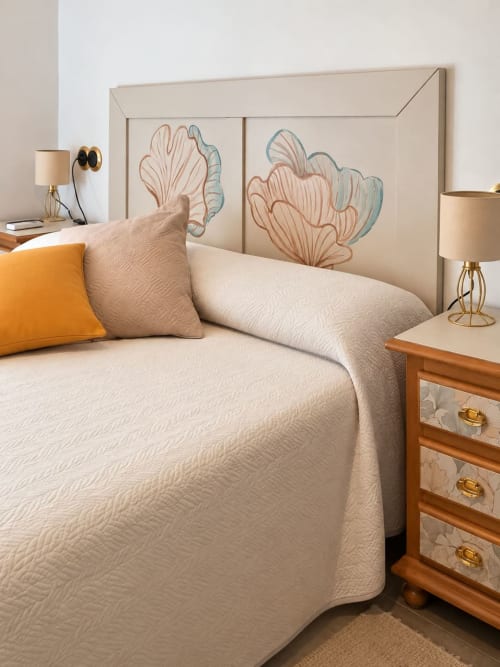 Bright bedroom at Refugio la Presa with cream bedding, coral botanical headboard art, orange accent pillow, and wooden
