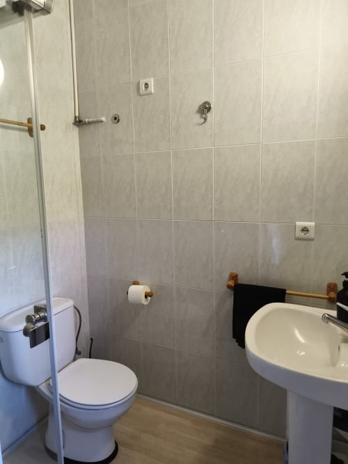 Clean bathroom with white pedestal sink, toilet, shower enclosure, and tiled walls at Balcó del Priorat hotel in Tarragona