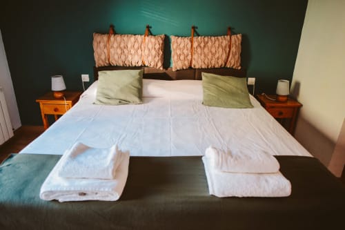 Double bed with white linens, peach headboard, and green pillows in a Tarragona hotel room with mountain views