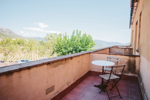 Private balcony at Balcó del Priorat hotel in Tarragona with mountain views, white table, and chairs overlooking vineyard