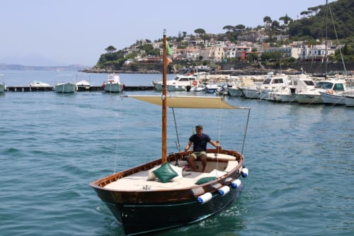 Tradizionale barca da pesca nel porto di Serrara Fontana con colorato villaggio costiero e barche ormeggiate