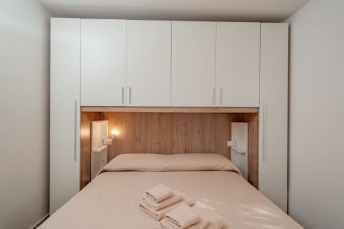 Camera moderna di Short Let's Olbia con letto queen size, armadi a muro e testata in legno con illuminazione integrata