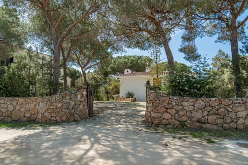 Ingresso villa in pietra con alberi mediterranei nella proprietà Short Let's di Olbia, Italia
