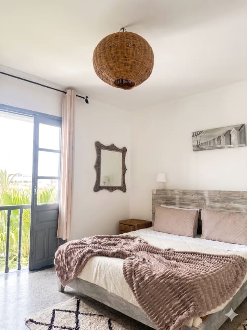 Chambre bohème à Yousurf Surfhouse avec suspension en rotin, lit en bois et vue sur le balcon à Essaouira