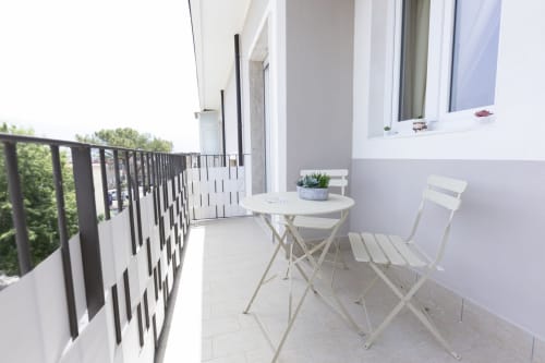 Balcone dell'Aurum Nolana Suites a Pompei con tavolo bianco, sedie e vista sulla città dalla camera deluxe