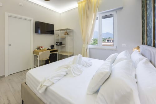 Camera luminosa presso Aurum Nolana Suites con letto matrimoniale, TV, scrivania e viste sui Monti Vesuvio e Pompei
