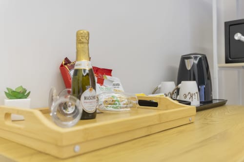 Scrivania in legno con bottiglia di champagne, calici e amenities di benvenuto presso l'Aurum Nolana Suites a Pompei