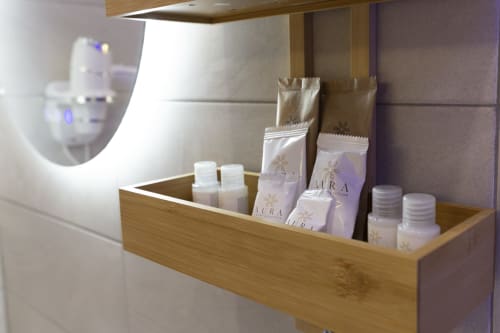 Ripiano in legno con amenities della collezione AURA e articoli da toilette nella suite Aurum Nolana, Pompei