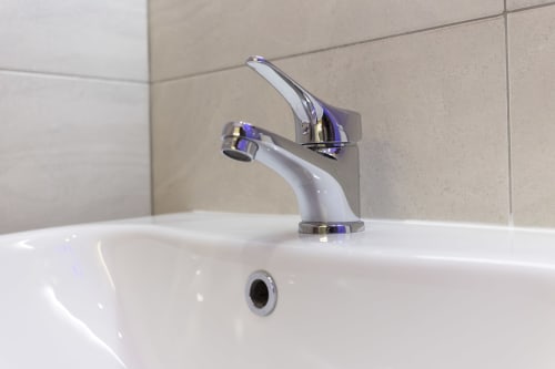 Moderno rubinetto cromato su lavandino bianco in bagno presso Aurum Nolana Suites a Pompei, con pareti piastrellate beige