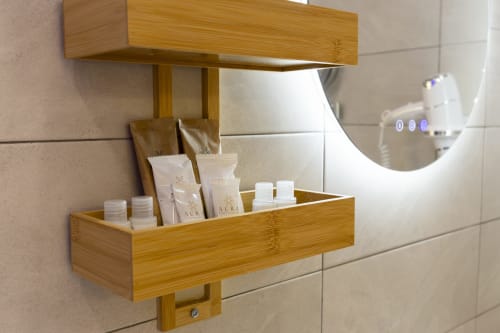 Mensola in legno con prodotti per l'igiene AURA presso Aurum Nolana Suites, Pompei, accanto a specchio illuminato