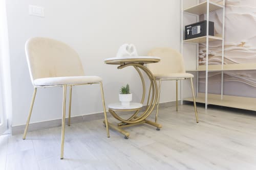 Zona living moderna in Aurum Nolana Suites Pompei con sedie color crema, tavolo in ottone e libreria con vista sul Vesuvio