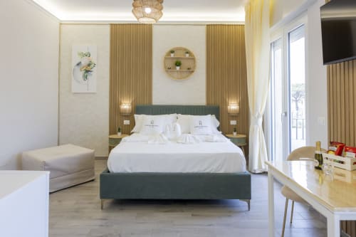 Camera elegante presso l'Aurum Nolana Suites di Pompei con arredamento moderno, biancheria bianca, balcone con vista montagna
