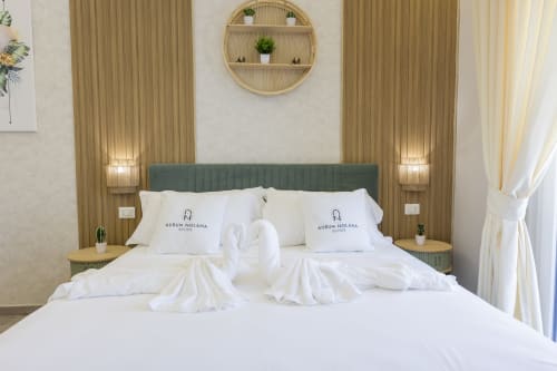 Camera da letto lussuosa ad Aurum Nolana Suites a Pompeii con testata verde, biancheria bianca e cigni decorativi in asciugamani