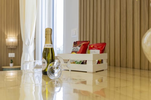 Amenità di benvenuto della suite executive presso Aurum Nolana Suites a Pompei con champagne, bicchieri e stuzzichini su tavolo in marmo