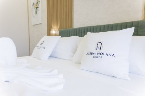 Camera dell'Aurum Nolana Suites con cuscini bianchi, testata verde e vista sulla montagna a Pompei