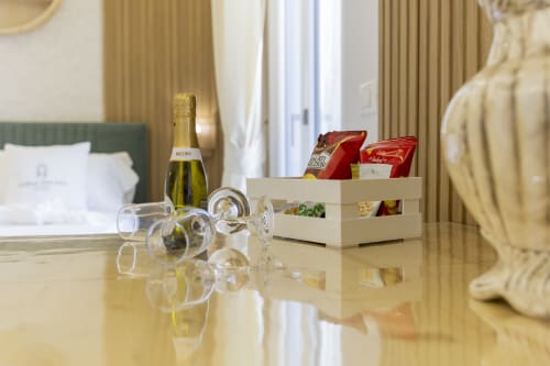 Suite elegante all'Aurum Nolana Suites di Pompei con champagne, cesto benvenuto e scrivania in marmo con vista montagna