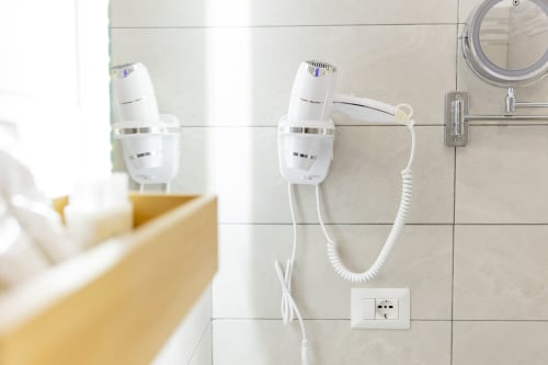 Asciugacapelli a parete e servizi di cortesia nel bagno dell'Aurum Nolana Suites a Pompei, con rivestimento in piastrelle e specchio