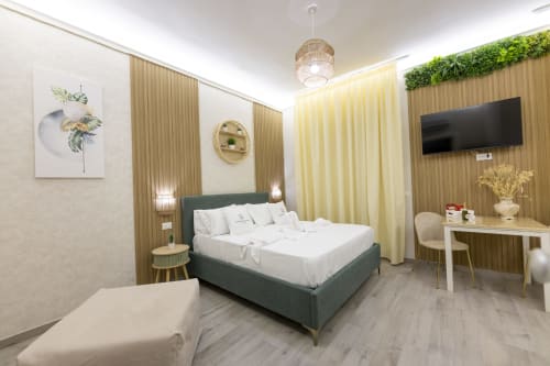 Suite Executive Tripla Aurum Nolana a Pompei con letto verde, tende gialle, scrivania, TV e comfort moderni